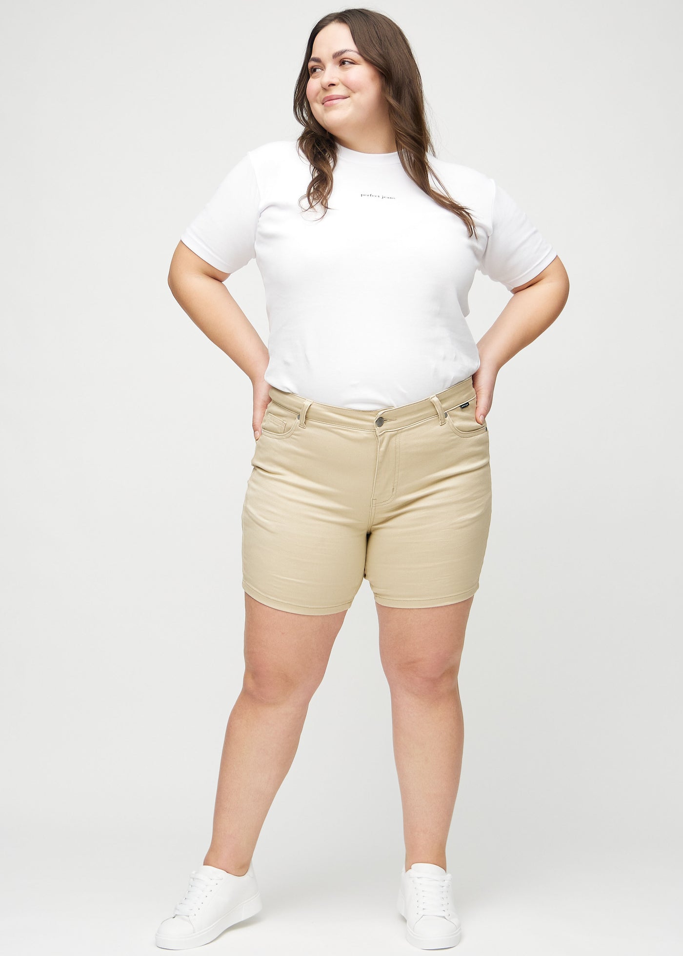 Fuldt billede af en plus-size model i beige skinny short shorts.