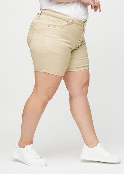 Beige skinny short shorts set fra siden på en plus-size model.