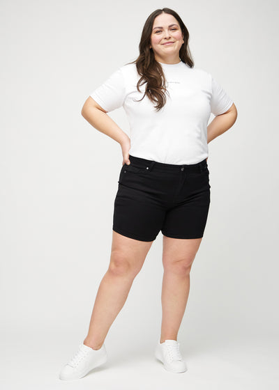 Fuldt billede af en plus-size model i sorte skinny middle shorts.