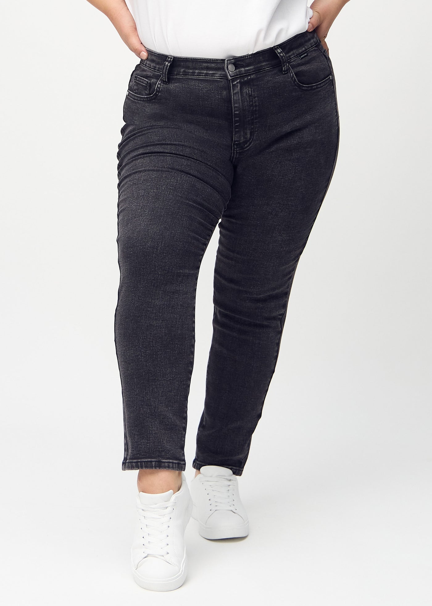 Mørkegrå denim slim jeans, modelnavn Shadows, som sidder tæt til benet, dog lidt løsere ved anklen, på en plus-size model, set forfra.