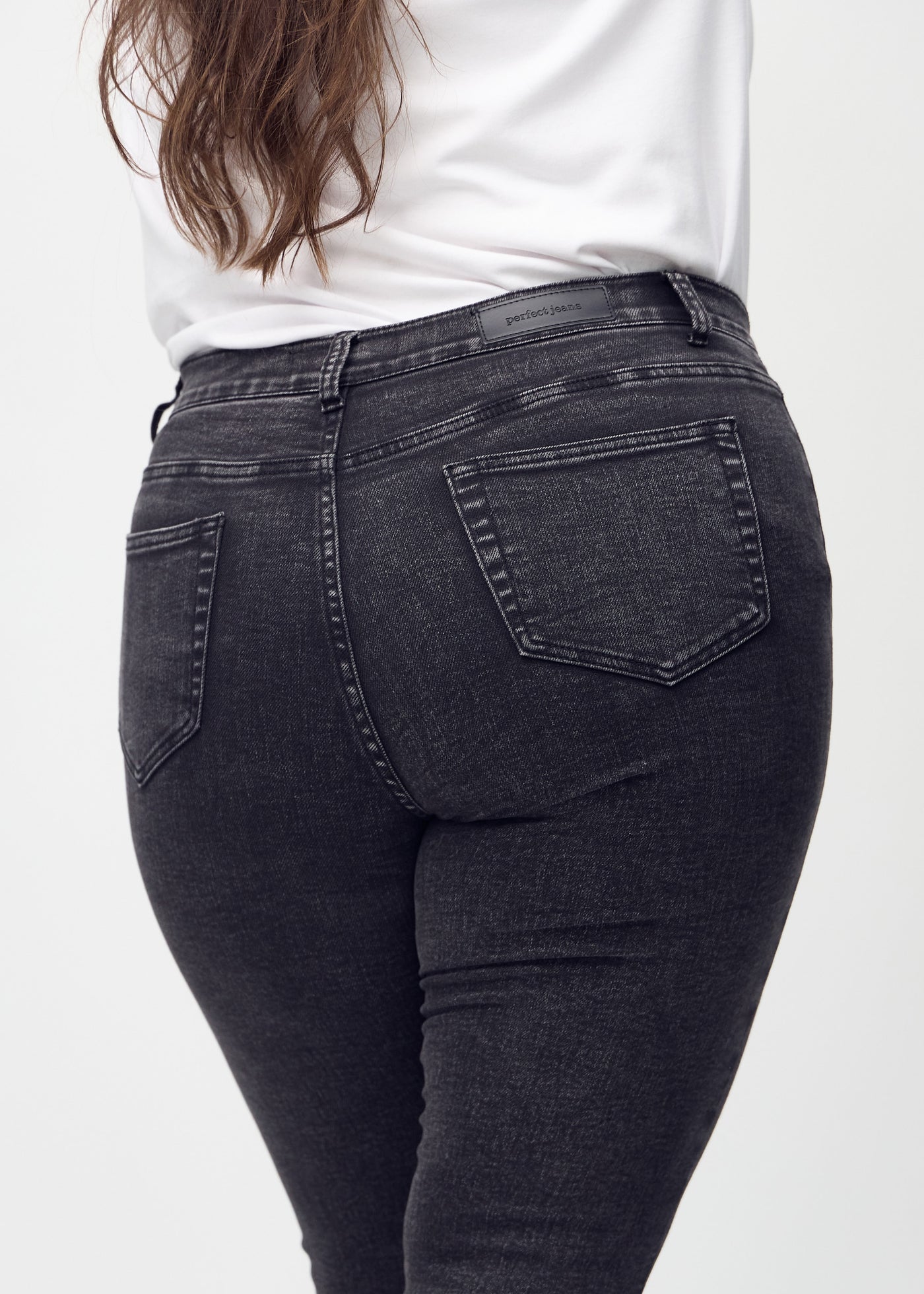 Mørkegrå denim skinny jeans set bagfra tæt på en plus-size model for at vise detaljer.