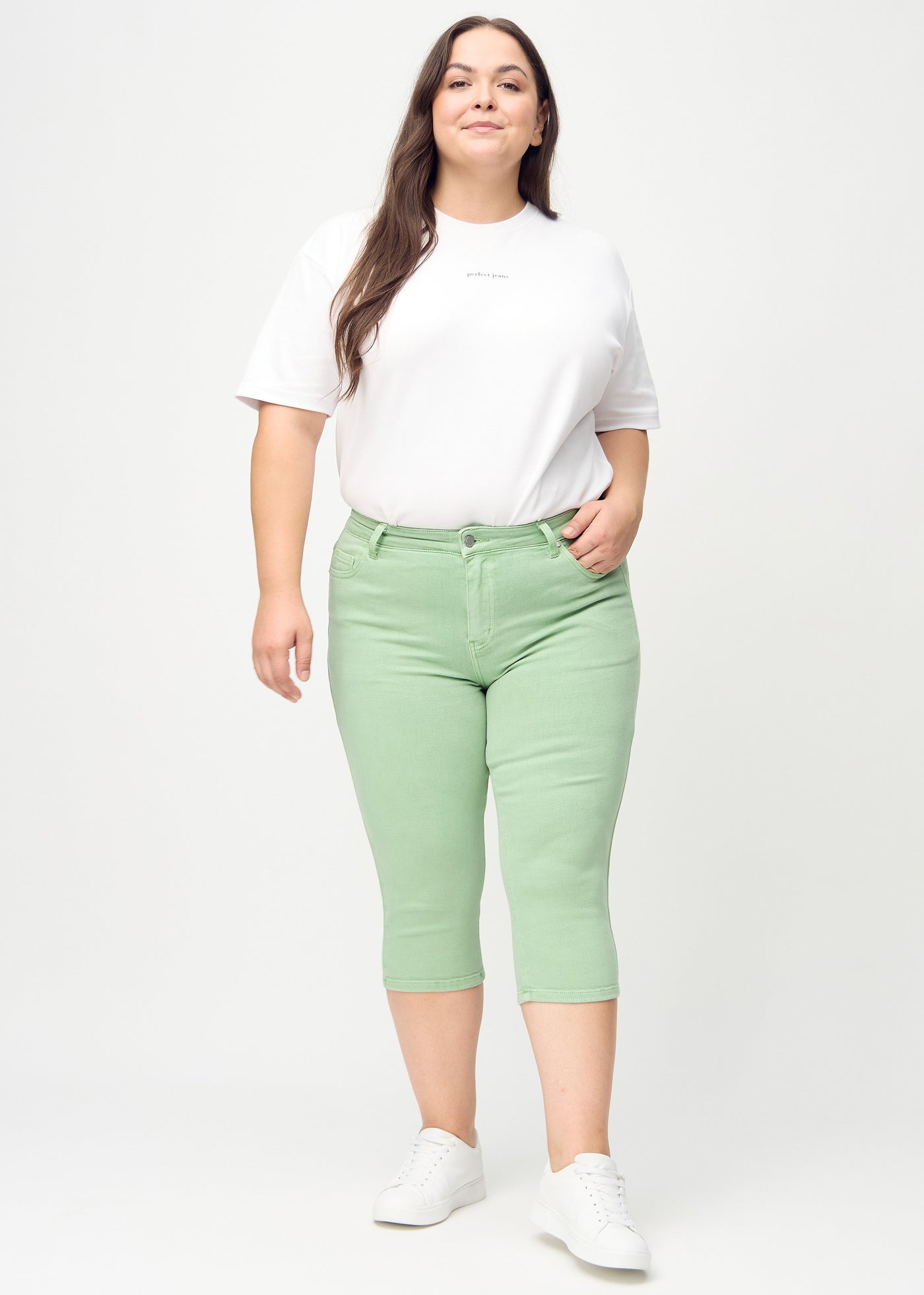 Fuldt billede af en plus-size model i lysegrønne skinny capris.