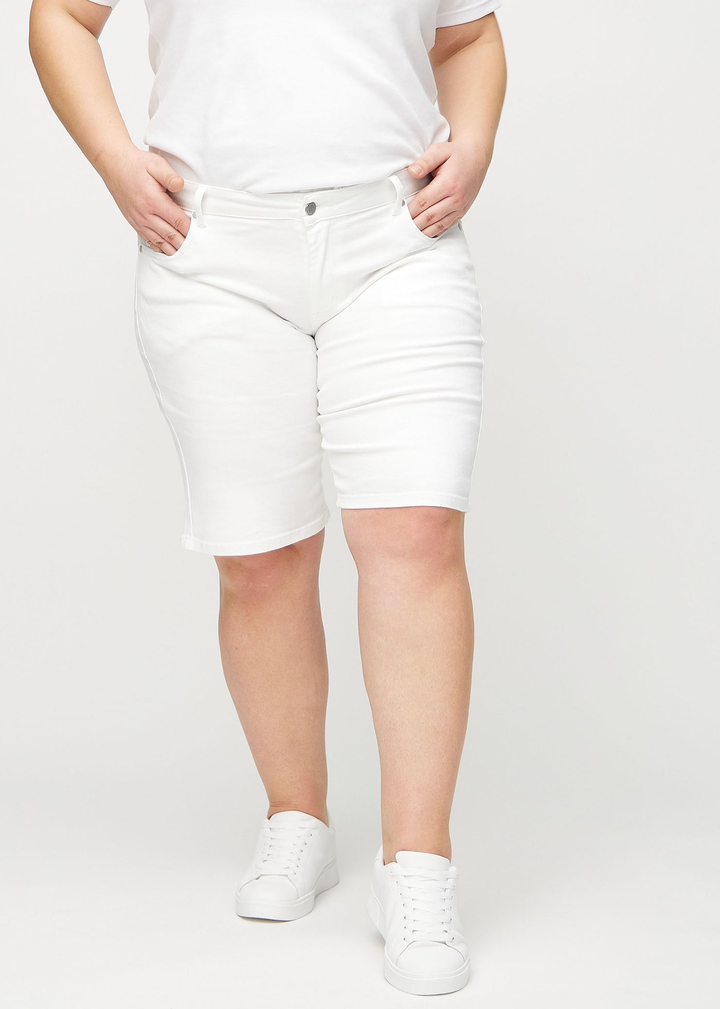 Hvide regular middle shorts, modelnavn Marguerites, som går lige ned langs benet og slutter lige over knæet på en plus-size model, set forfra.