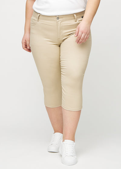 Beige skinny capris, modelnavn Gazelles, som sidder tæt til benet og slutter lige under knæet på en plus-size model, set forfra.