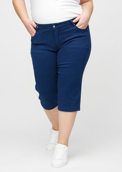 Mørkeblå regular capris, modelnavn Royals, som sidder lige til benet og slutter lige under knæet på en plus-size model, set forfra.