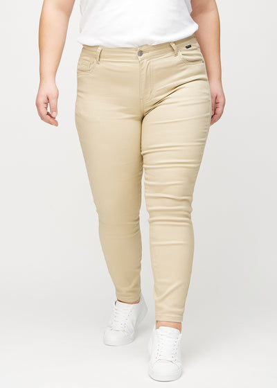 Beige skinny jeans, modelnavn Gazelles, som sidder tæt til benet på en plus-size model, set forfra.