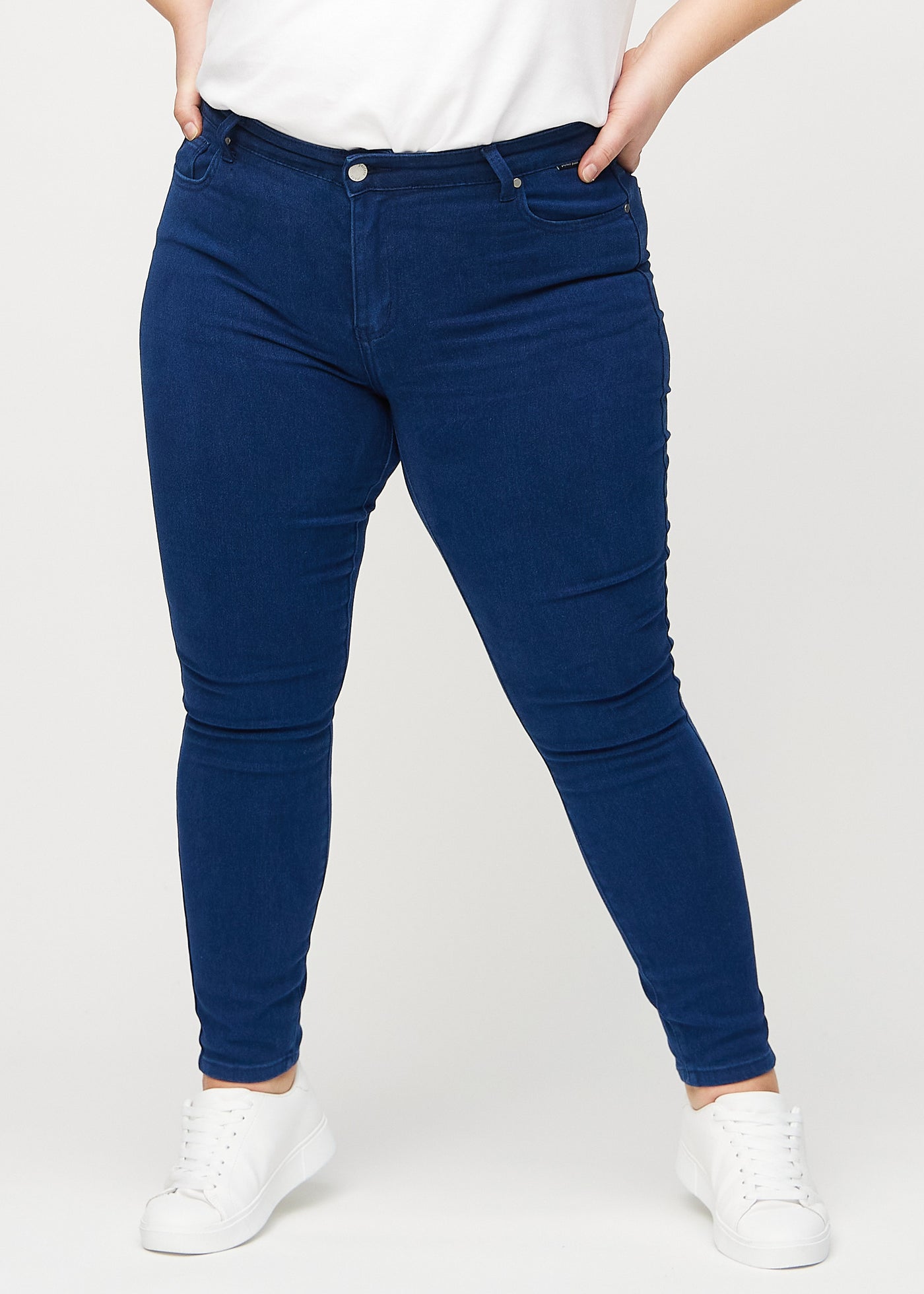 Mørkeblå skinny jeans, modelnavn Royals, som sidder tæt til benet på en plus-size model, set forfra.