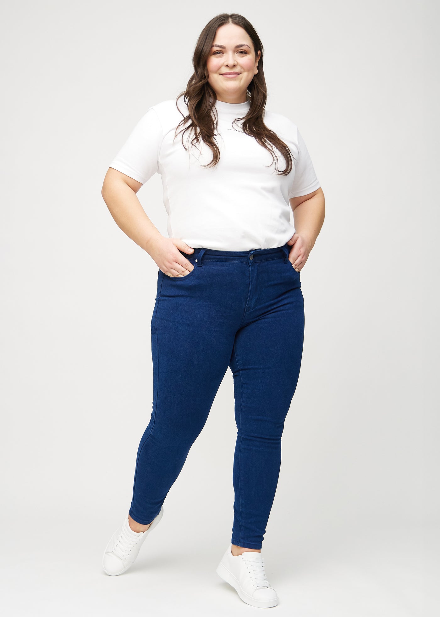 Fuldt billede af en plus-size model i mørkeblå skinny jeans.