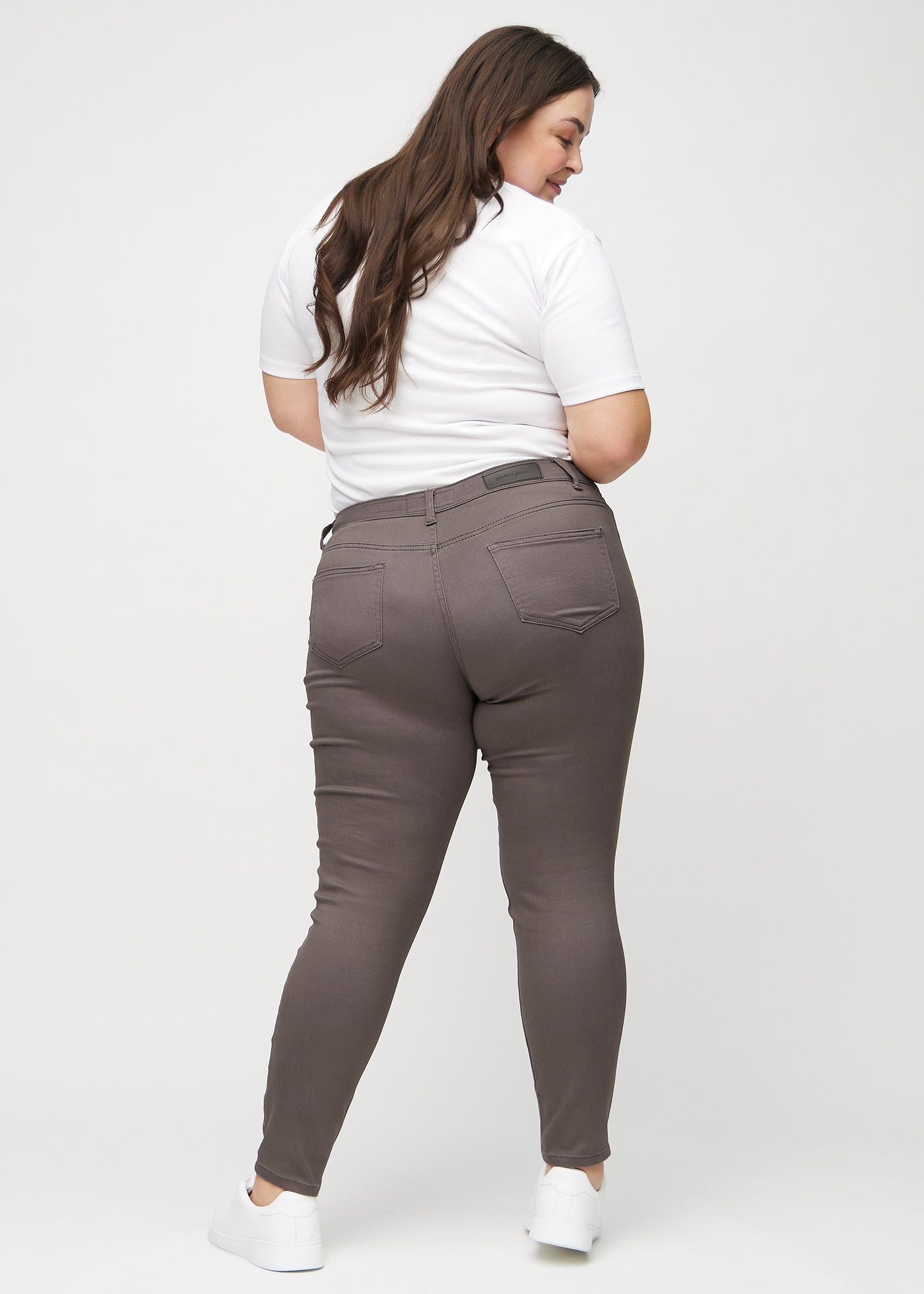 Gråbrune skinny jeans set bagfra på en plus-size model, så man kan se hele produktet.