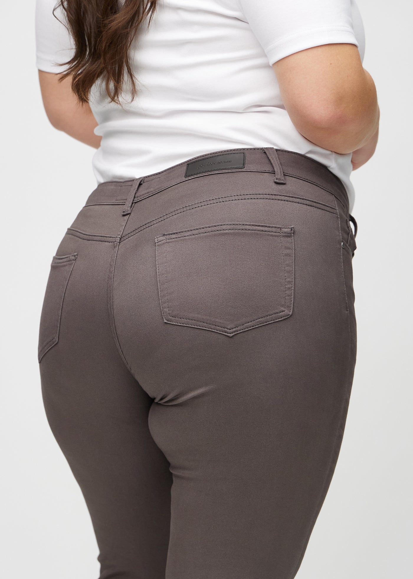 Gråbrune skinny jeans set bagfra tæt på en plus-size model for at vise detaljer.