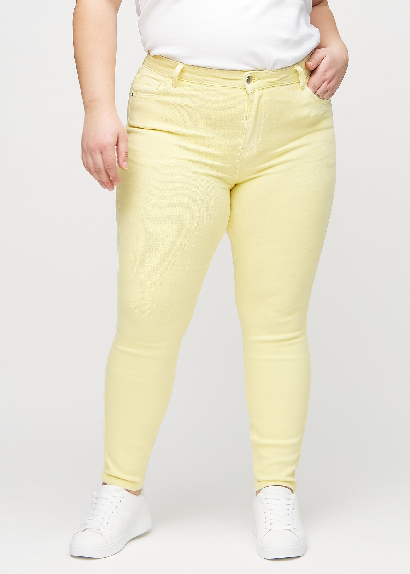 Lysegule skinny jeans, modelnavn Lemonades, som sidder tæt til benet på en plus-size model, set forfra