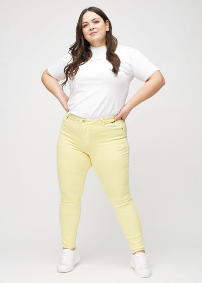 Fuldt billede af en plus-size model i lysegule skinny jeans.