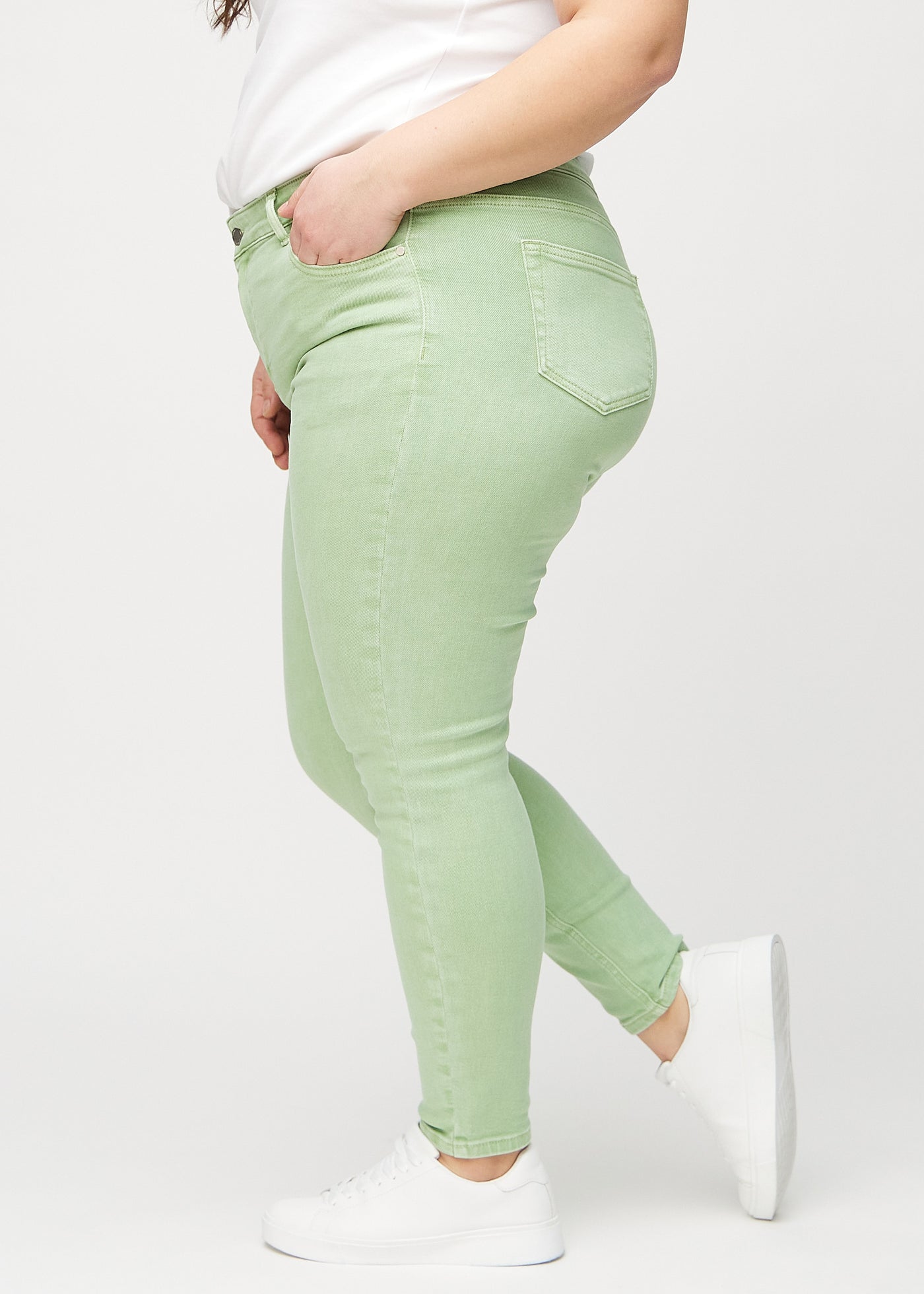 Lysegrønne skinny jeans set fra siden på en plus-size model.