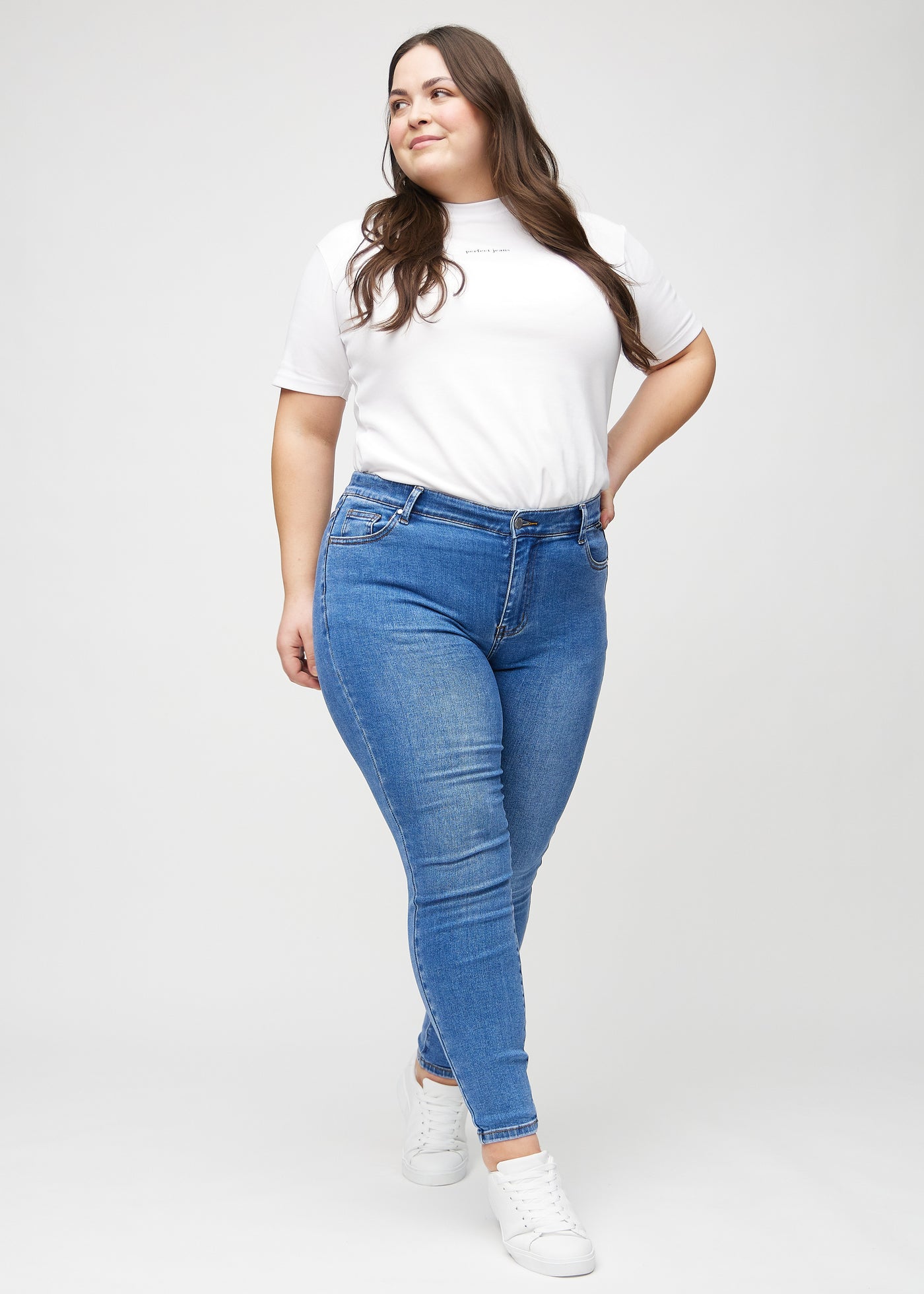 Fuldt billede af en plus-size model i denim skinny jeans.