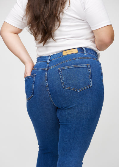 Mørk denim skinny jeans set bagfra tæt på en plus-size model for at vise detaljer.