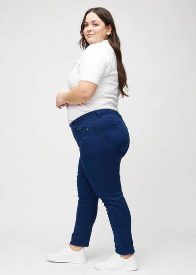 Mørkeblå slim jeans set fra siden på en plus-size model.