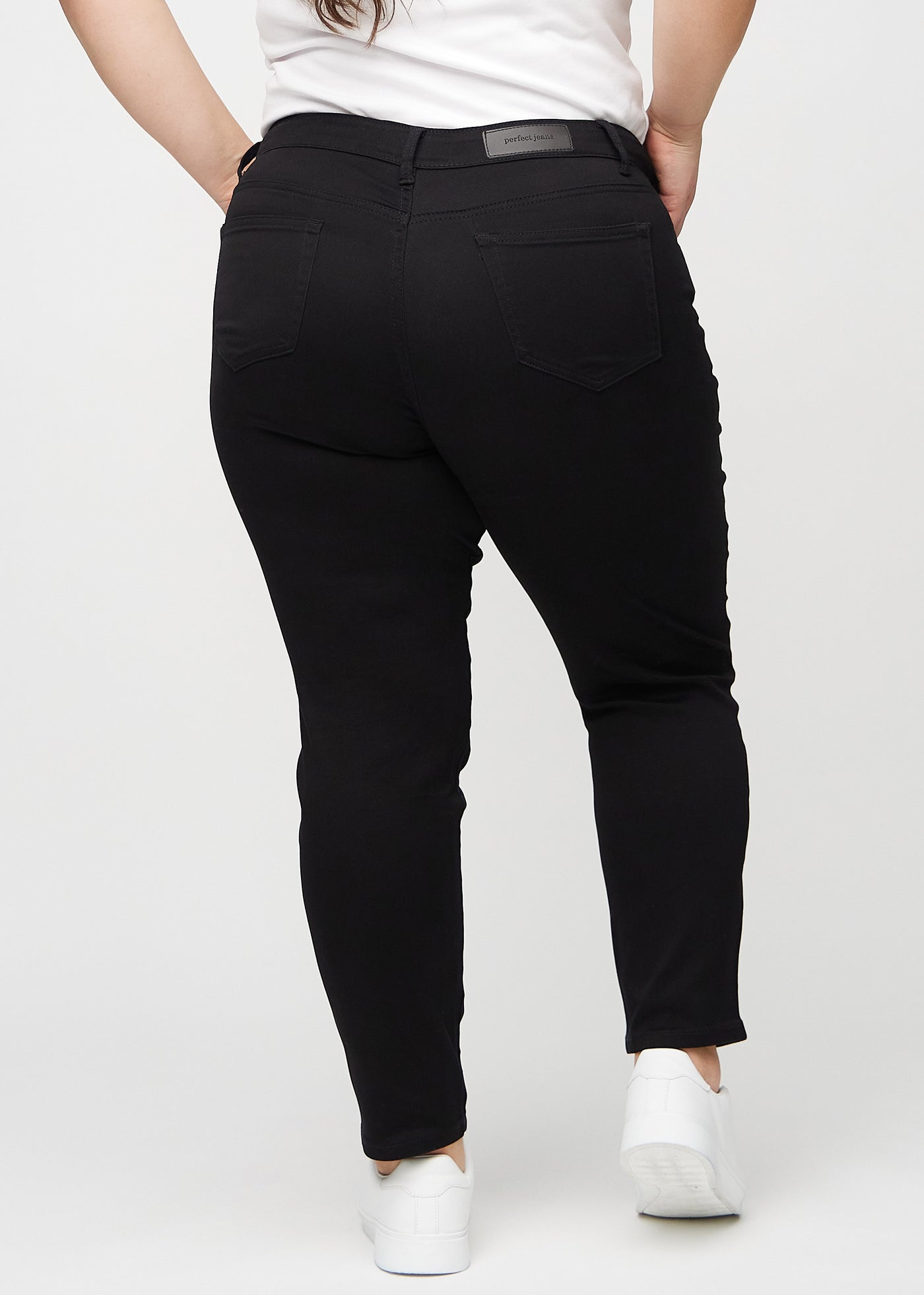 Sorte slim jeans set bagfra på en plus-size model, så man kan se hele produktet.