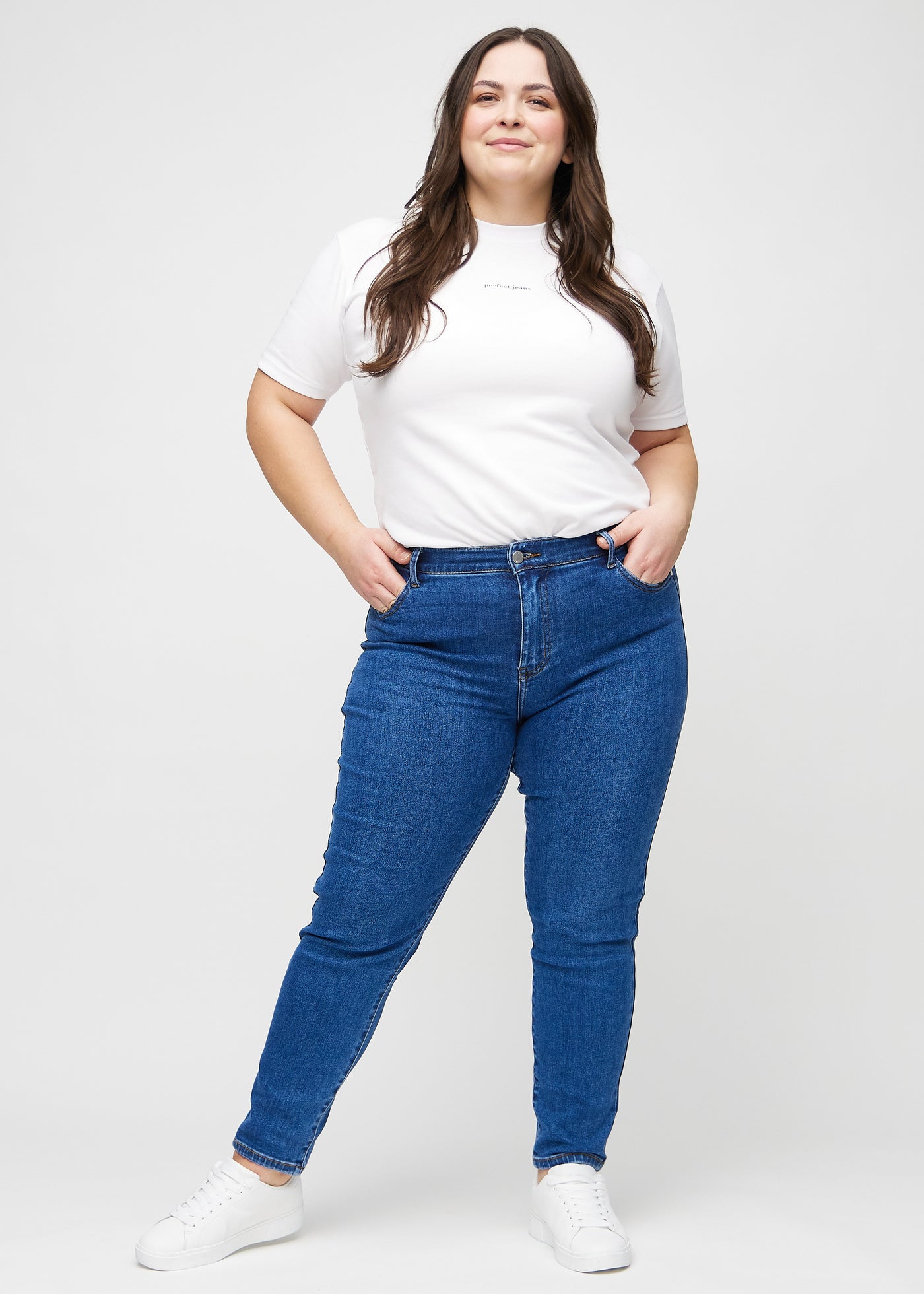 Fuldt billede af en plus-size model i mørk denim slim ultra high rise jeans.