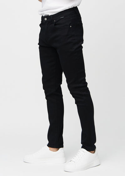 Sorte slim jeans set fra siden på model.