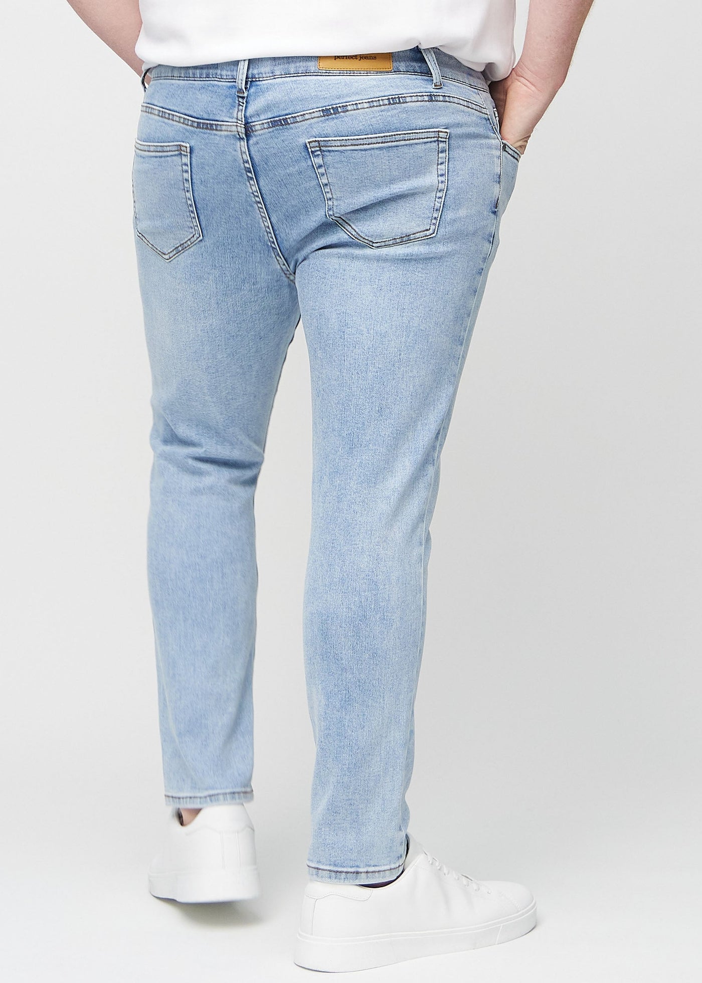 Lys denim slim jeans set bagfra på en plus-size model, så man kan se hele produktet.