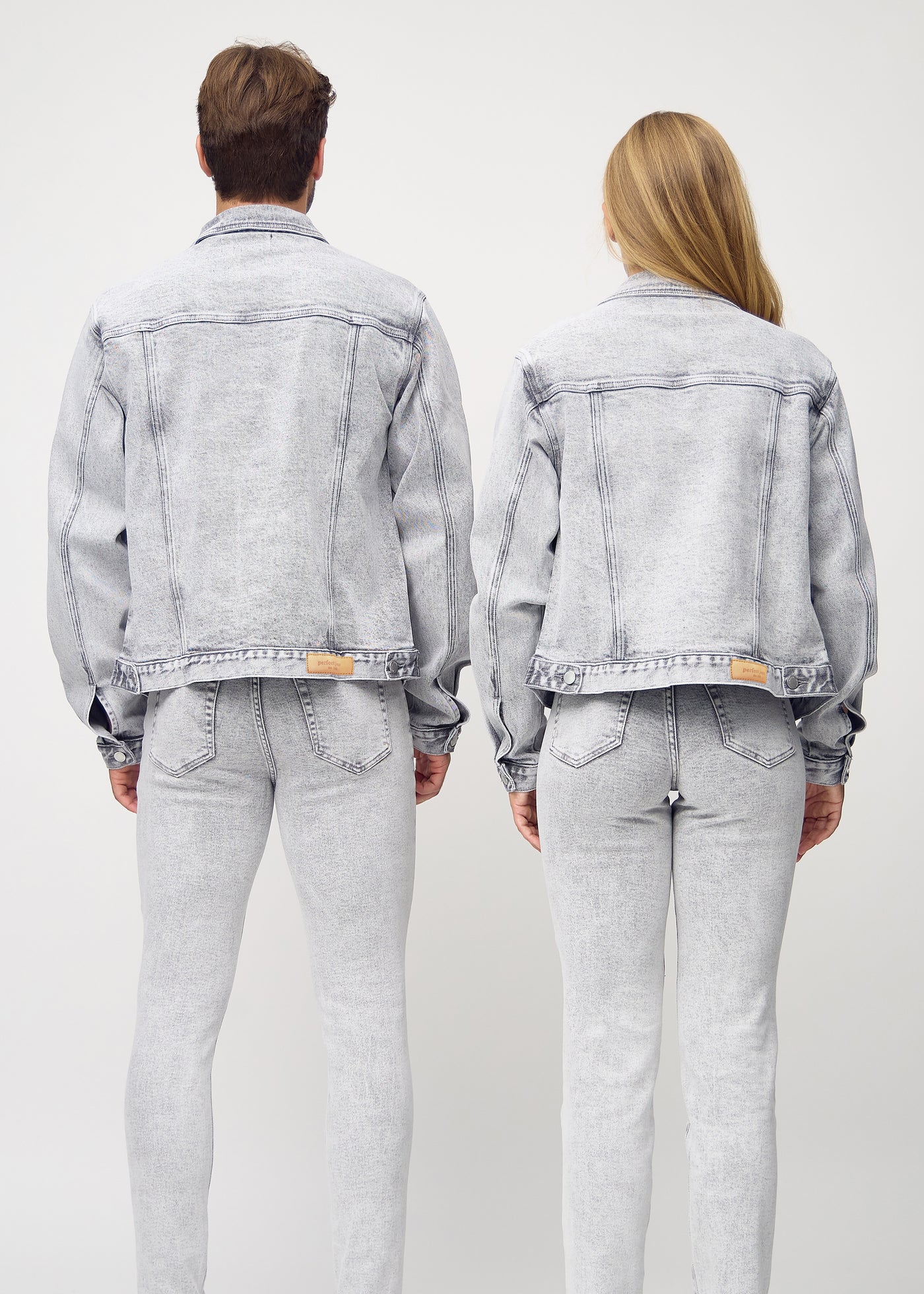 Unisex lysegrå denim jakke set bagfra på mand og kvinde, viser rygdetaljer og højkvalitetssømme.