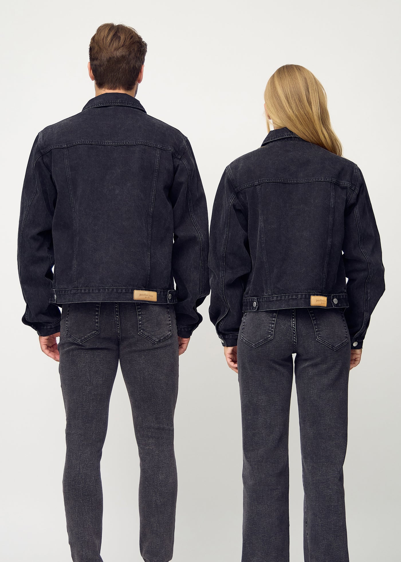 Unisex mørkegrå denim jakke set bagfra, viser rygdetaljer og sømme i høj kvalitet på mand og kvinde.
