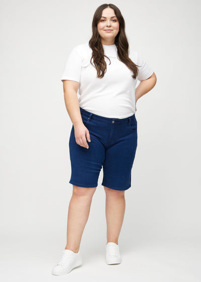 Plus-size model går ind i billedet, strækker i sine shorts, viser dem frem ved at dreje rundt, og forlader derefter billedet.