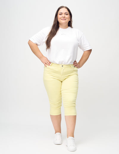 Plus-size model går ind i billedet, strækker i sine capris, viser dem frem ved at dreje rundt, og forlader derefter billedet.