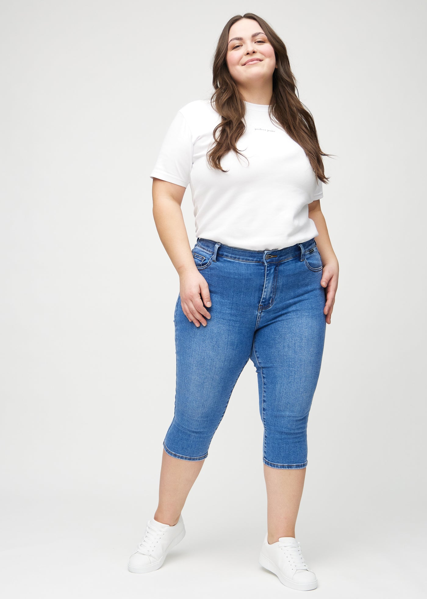 Plus-size model går ind i billedet, strækker i sine capris, viser dem frem ved at dreje rundt, og forlader derefter billedet.