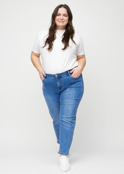 Plus-size model går ind i billedet, strækker i jeansene, viser dem frem ved at dreje rundt, og forlader derefter billedet.