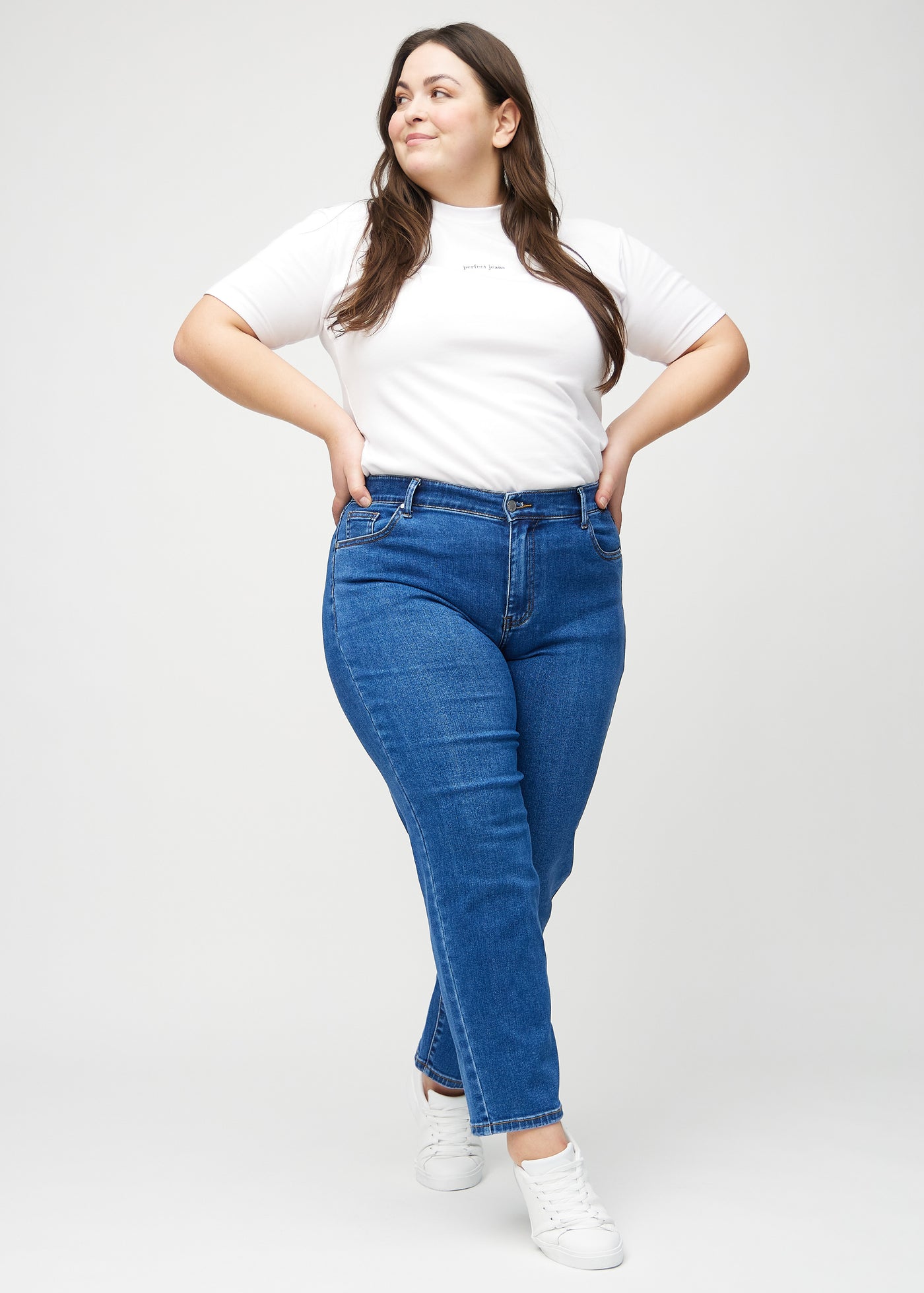 Plus-size model går ind i billedet, strækker i jeansene, viser dem frem ved at dreje rundt, og forlader derefter billedet.